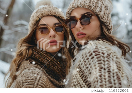 Two women in winter attire posing outdoors in snow 116522001
