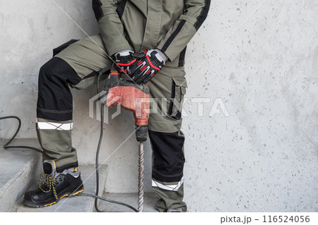 Man builder in workwear with electric hammer drill Man builder in workwear with electric hammer drill 116524056