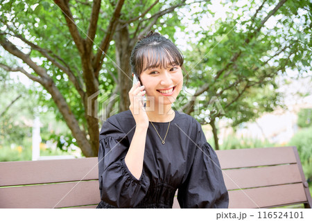 ベンチで電話をする女子大学生 ベンチで電話をする女子大学生 116524101