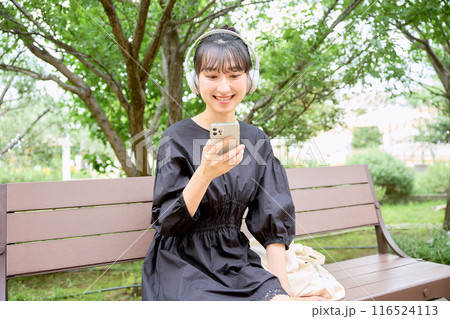 ベンチで音楽を聴く女子大学生 116524113