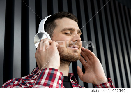 Attractive young guy listens to music in headphones Attractive young guy listens to music in headphones 116525494