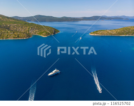 Scenic aerial view many yachts boats moored at Croatian bay harbor shore blue turquoise clear water at bright summer sunny day. Top above Mediterranean sea marina. Boat vessel charter service 116525702