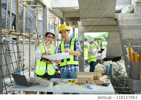 Specialists team in safety vest and helmet discussing structure of the building at construction site 116527861