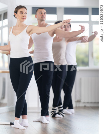 Group of dancers stand in fifth position at barre Group of dancers stand in fifth position at barre 116529672