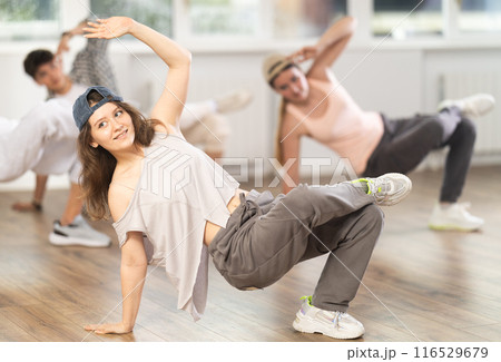 Girl and her students perform hip hop dance on one bent leg, movement in horizontal plane near floor Girl and her students perform hip hop dance on one bent leg, movement in horizontal plane near floor 116529679