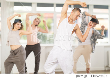 Young man standing performs basic hip hop movements in front of group of students Young man standing performs basic hip hop movements in front of group of students 116529897