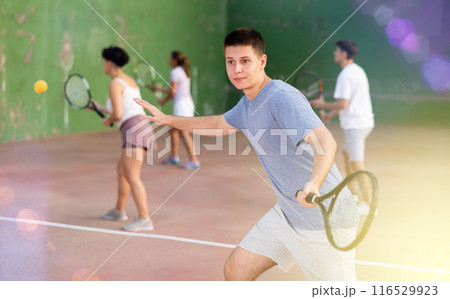 Male sportsman preparing to hit ball with racket. Frontenis game on outdoor court 116529923