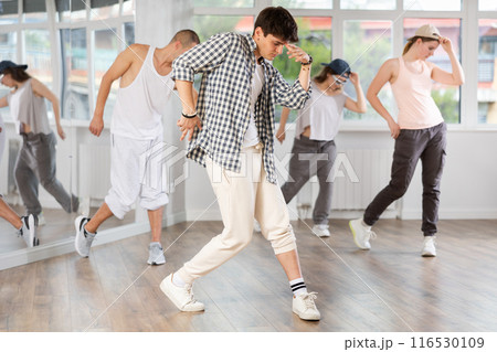 Young man standing performs basic hip hop movements in front of group of students 116530109