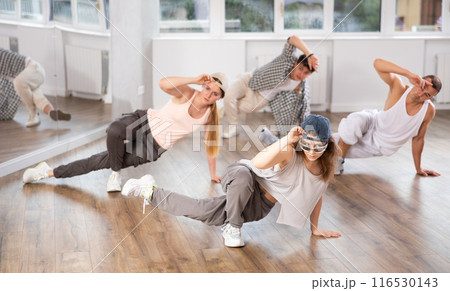 Concetrated guys and girls studying movement of contemporary dance in classroom with his friends 116530143