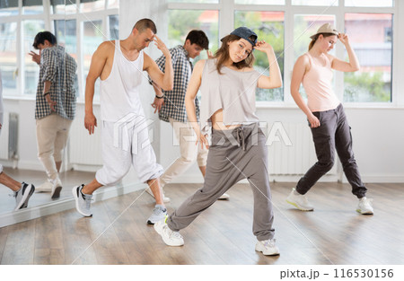 Young girl standing performs basic hip hop movements in front of group of students 116530156