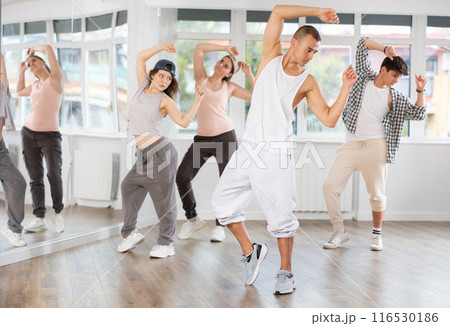 Young man standing performs basic hip hop movements in front of group of students Young man standing performs basic hip hop movements in front of group of students 116530186
