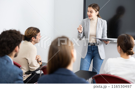 Portrait of young businesswoman standing near interactive board and participating in corporate seminar in auditorium Portrait of young businesswoman standing near interactive board and participating in corporate seminar in auditorium 116530497