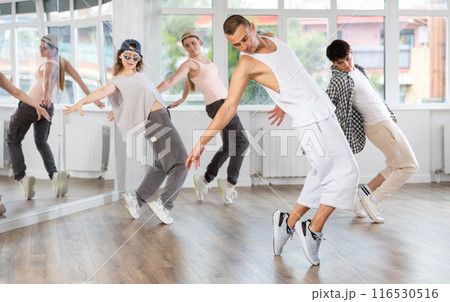 Young guy practicing hip hop slide moves in training hall 116530516