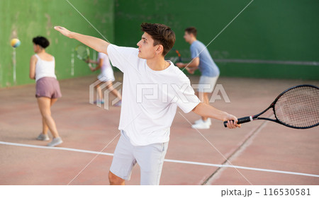Hispanic guy playing frontenis on open court on summer day Hispanic guy playing frontenis on open court on summer day 116530581