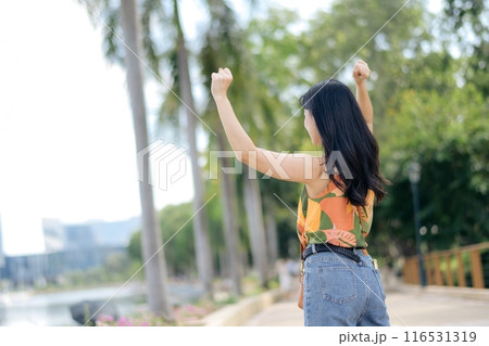 Embrace the calm and freedom of a lone traveler, a young woman in an orange shirt, navigating the road with happiness and grace. Embrace the calm and freedom of a lone traveler, a young woman in an orange shirt, navigating the road with happiness and grace. 116531319