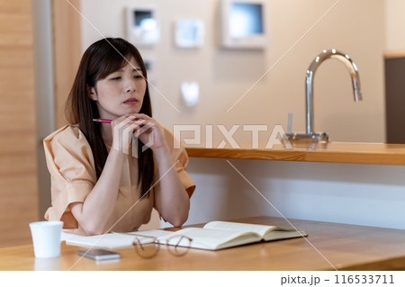 ダイニングテーブルで勉強中に悩むミドル女性 ダイニングテーブルで勉強中に悩むミドル女性 116533711