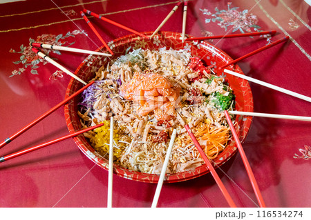 Serving of yusheng or yee sang with raw salmon belly during Chinese New Year with chop sticks laid around plate for good luck and prosperity Serving of yusheng or yee sang with raw salmon belly during Chinese New Year with chop sticks laid around plate for good luck and prosperity 116534274
