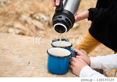 Family pouring hot drink into cups during an outdoor adventure 116535524