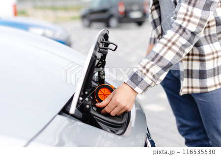 A young man opens the hood to charge his electric car 116535530