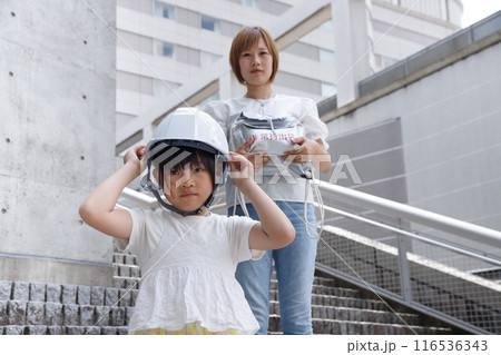 ヘルメットをかぶった小学生の女の子とママ。防災訓練に参加する。 116536343