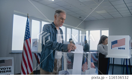 Adult Caucasian man puts bulletin paper in box after voting 116536532