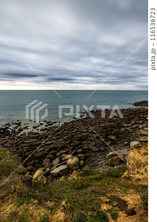 Scenic Rocky Shoreline Under Cloudy Sky, Perfect for Adventure or Relaxing Vacation 116536723
