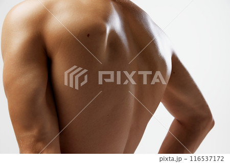 Cropped photo of toned, tanned and healthy man's back, with highlighted muscles against white studio background. 116537172
