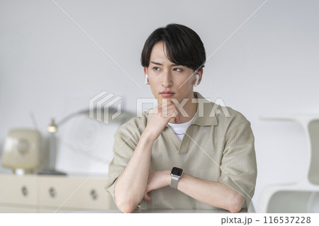 厳しい表情で考え込むイヤホンをした20代の男性 厳しい表情で考え込むイヤホンをした20代の男性 116537228
