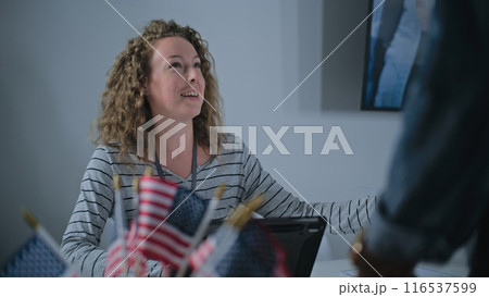 Female polling officer consults African American voter, uses tablet computer 116537599