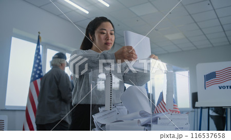 Asian young woman puts ballot paper in box during Election Day in the United States Asian young woman puts ballot paper in box during Election Day in the United States 116537658