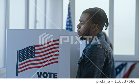 African American man stands and decides at voting booth African American man stands and decides at voting booth 116537660