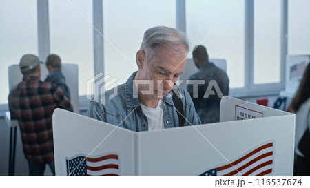 Mature man comes to vote in booth in polling station office Mature man comes to vote in booth in polling station office 116537674