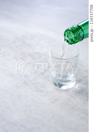 韓国の伝統的な蒸留酒、よく冷えた韓国焼酎（ソジュ）をグラスに注ぐ 116537706