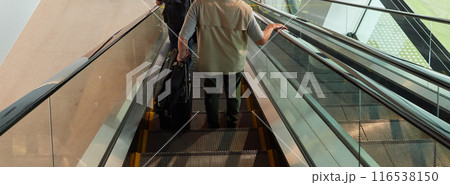 オフィスビルのエスカレーターに乗る若い男性とシニア男性の姿 オフィスビルのエスカレーターに乗る若い男性とシニア男性の姿 116538150