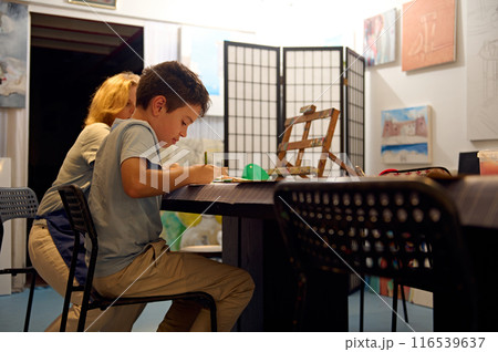 Children engaged in art class with teacher, drawing and painting at workshop 116539637