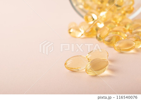 Omega 3 fish oil on pink background. Vitamins in soft capsules, cod liver oil closeup. Concept of healthcare, supplements, vitamin D, treatment of diseases. Copy space, banner. High quality photo 116540076