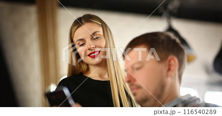 Smiling pretty blonde showing photo in smartphone to man Smiling pretty blonde showing photo in smartphone to man 116540289