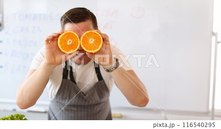 Man holding cut oranges at eye level instead of glasses 116540295