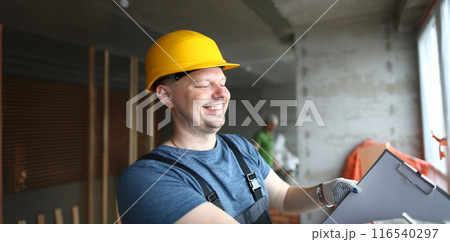 Smiling builder holding clipboard and write down needed work material for renovation 116540297