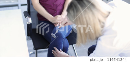 Doctor neurologist checking knee reflexes of female patient using percussion hammer in clinic Doctor neurologist checking knee reflexes of female patient using percussion hammer in clinic 116541244