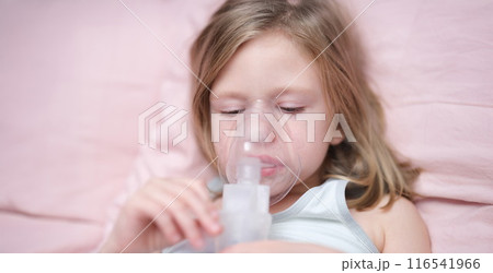 Little sad girl having inhalation for easing cough 116541966