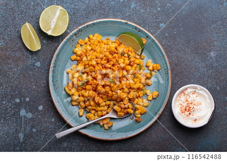Plate of esquites mexican street corn salad with chili, mayonnaise, and lime on dark stone background Plate of esquites mexican street corn salad with chili, mayonnaise, and lime on dark stone background 116542488