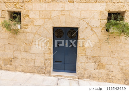Image of an old, worn door in a Mediterranean house facade 116542489
