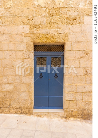Image of an old, worn door in a Mediterranean house facade 116542491