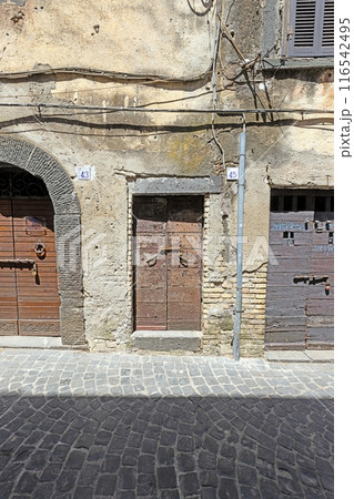 Image of an old, worn door in a Mediterranean house facade 116542495