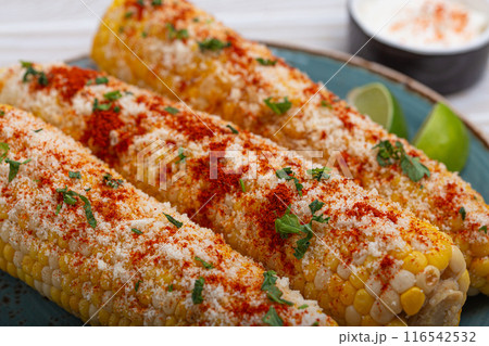 Delicious Mexican dish Elotes corn cob covered in spices and cheese Delicious Mexican dish Elotes corn cob covered in spices and cheese 116542532