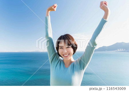 海を背景に背伸びする女性 116543009