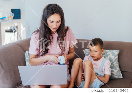 Stressed mother talking with pediatrician doctor during online video chat on pc, worried about her son's health, checking child's temperature by holding hand on kid forehead. Telemedicine, telehealth. 116543402