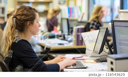 administrative staff working at their desks in an office environment 116543629