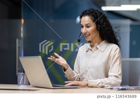 Happy businesswoman with headset having virtual meeting on laptop. Professional interacting in office setting, working on project, providing customer support or attending online conference. Happy businesswoman with headset having virtual meeting on laptop. Professional interacting in office setting, working on project, providing customer support or attending online conference. 116543689